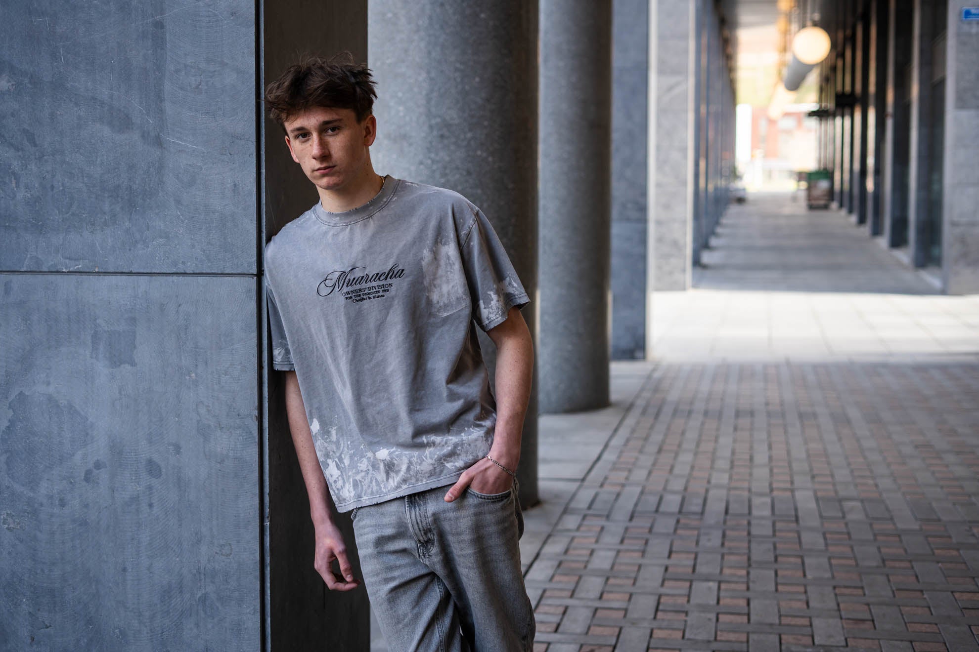 MUARACHA Script Tee Grey Washed model in urban architecturale setting - oversized relaxed fit heavyweight cotton