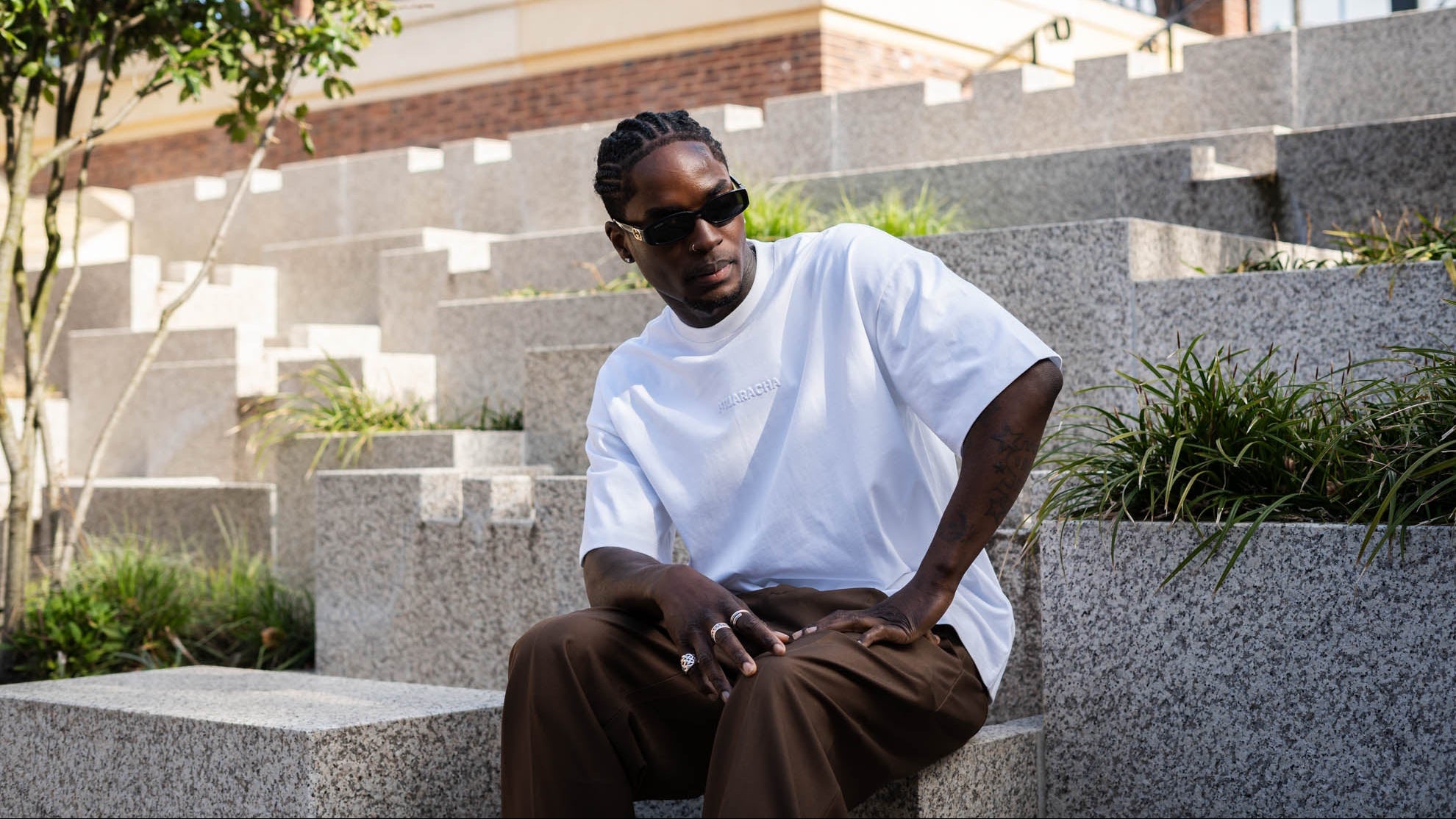 MUARACHA model in white oversized tee and cacao-brown wide-leg trousers, urban city setting — elevated everyday wear
